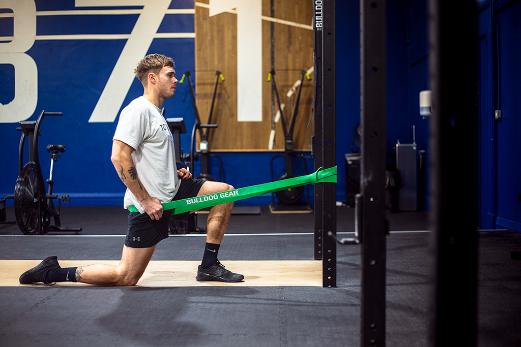 Man using Bulldog Gear resistance band for rig assisted stretching